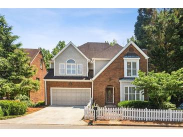 Charming two-story brick home with a manicured lawn, white picket fence and attached two-car garage at 2567 Briers North Dr, Dunwoody, GA 30360