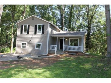 Charming two-story home with a covered porch and neutral siding surrounded by lush trees at 5561 Petite Pt, Lithonia, GA 30058