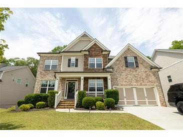 Charming two-story brick home with a welcoming front porch and well-manicured landscaping on a sunny day at 3589 Tamerton Trce, Buford, GA 30519