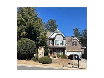 Charming two-story home featuring a manicured lawn, mature trees, and a brick and siding facade on a sunny day at 121 Royal Sunset Dr, Dallas, GA 30157