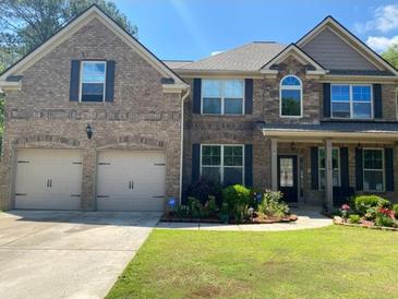 Charming two-story brick home featuring an attached two-car garage, covered porch and lush landscaping at 200 Birchwood Dr, Loganville, GA 30052