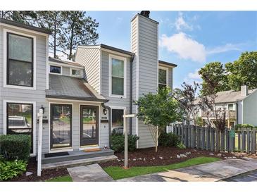 Charming two-story townhouse with grey siding, black trim, a chimney, and a well-manicured front yard at 1027 Riverbend Club Se Dr, Atlanta, GA 30339