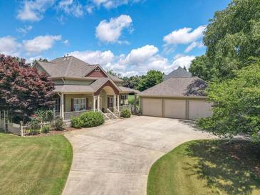 Inviting home with a spacious driveway and attached three-car garage, surrounded by lush greenery and trees at 105 Whippoorwill Way, Fayetteville, GA 30215