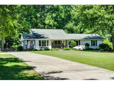 Charming one-story home with a long driveway and lush green lawn surrounded by mature trees at 290 Dania Dr, Alpharetta, GA 30009
