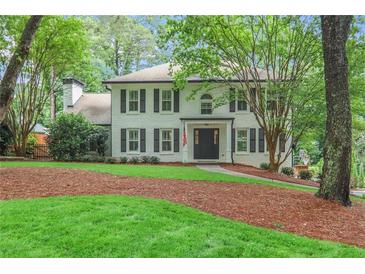 Charming white brick two-story home featuring black shutters, a well-manicured lawn, and mature trees at 3323 Lancing Ct, Duluth, GA 30096