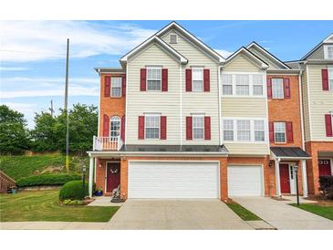 Attractive townhouse featuring a two-car garage, neutral siding, red shutters, and a well-maintained lawn at 5989 Turfway Park Ct, Sugar Hill, GA 30518