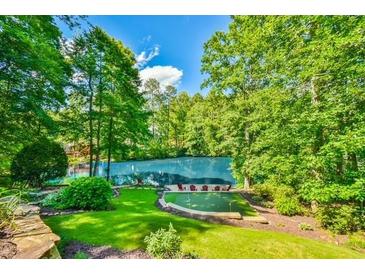 Secluded backyard featuring lush greenery, putting green, and lake views at 5675 Habersham Vly, Suwanee, GA 30024