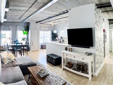 Bright living room features a dining area, hardwood floors, exposed pipes, and natural light from large windows at 800 Peachtree Ne St # 1319, Atlanta, GA 30308
