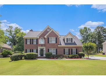 Charming two-story brick home with lush lawn, manicured landscaping, and a symmetrical facade under a bright, blue sky at 1644 Beaver Creek Ln, Snellville, GA 30078