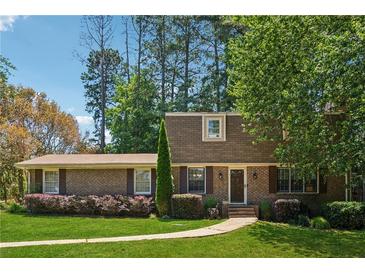Charming brick home featuring manicured lawn, mature trees, and inviting front entrance at 461 Village Green Sw Ct, Lilburn, GA 30047