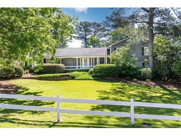 Charming gray home featuring a well-manicured front lawn, complemented by a classic white picket fence at 3099 Farmington Se Dr, Atlanta, GA 30339