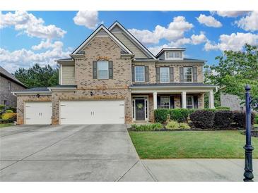 Charming brick two-story home with a manicured front lawn, three car garage, and covered front porch at 4191 Secret Shoals Way, Buford, GA 30518