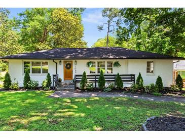 Charming single-story home featuring a white brick exterior, manicured lawn and well-maintained landscaping at 1790 Shirley Sw St, Atlanta, GA 30310