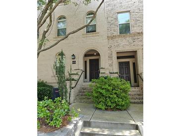 Charming townhome featuring a brick facade, arched entryway, and well-maintained landscaping at 1199 Lavista Ne Rd, Atlanta, GA 30324