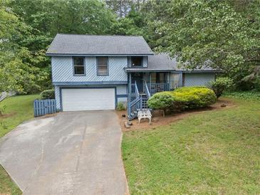Charming two-story home featuring a front yard, attached garage, and mature trees at 9760 Loblolly Ln, Roswell, GA 30075