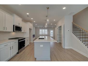 Bright open kitchen boasts an island with sink, stainless appliances, and stylish pendant lighting at 3338 Cranston Ln, Kennesaw, GA 30144