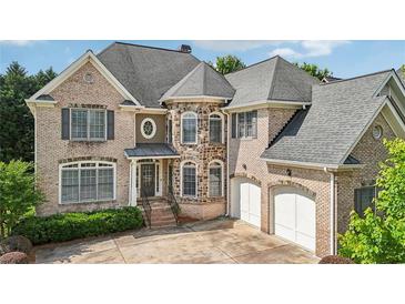 Charming brick home featuring a manicured lawn, multiple windows, and an attached two-car garage at 2871 Trailing Ivy Way, Buford, GA 30519