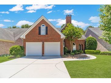 Charming brick home featuring a two-car garage, manicured lawn, and beautiful landscaping at 980 Windsor Place Cir, Grayson, GA 30017
