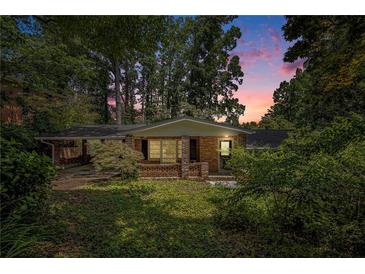 Charming single-story brick home featuring an attached carport and lush, mature landscaping at dusk at 2595 Woodhill Cir, Atlanta, GA 30344