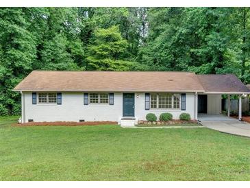 Charming brick home features a manicured lawn, updated windows, and a convenient carport at 5689 Woodland Dr, Acworth, GA 30102