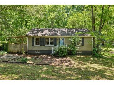 Charming single-story home with lush landscaping, and a covered parking area, nestled amongst mature trees at 1410 Cobb Branch Dr, Decatur, GA 30032