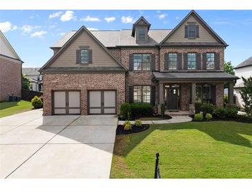 Beautiful brick home featuring a manicured lawn, two-car garage, and covered front porch at 3317 Sweetleaf Ln, Buford, GA 30519