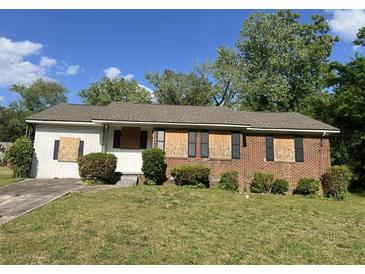 Exterior of a single story home with brick and siding, a lawn, and boarded up windows at 5286 Joan Of Arc Pl, Atlanta, GA 30349