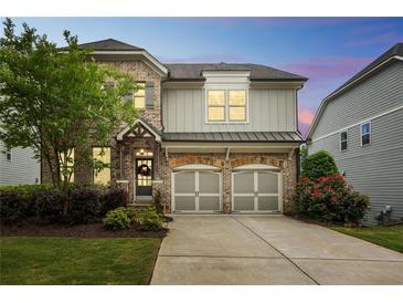 Charming two-story home with brick and siding, a two-car garage, and a well-manicured lawn at 935 Grove Valley Drive Dr, Cumming, GA 30041