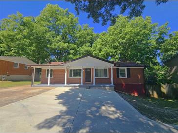 Charming brick home featuring a covered front porch with classic column detailing and a wide driveway at 1150 Goldsmith Rd, Stone Mountain, GA 30083