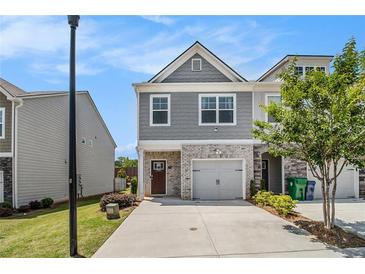 Charming townhome featuring gray siding, brick accents, and an attached one car garage and driveway at 1884 Plainsboro Dr, Lithonia, GA 30058