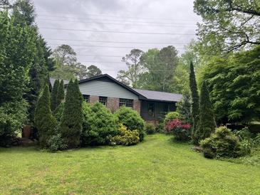 Charming single-story home surrounded by lush greenery and mature trees, creating a private and serene setting at 7235 Thornhill Ne Ln, Atlanta, GA 30328