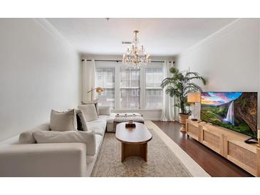 Bright living room features a chandelier, white couch, and hardwood floors at 1850 Cotillion Dr # 2304, Dunwoody, GA 30338