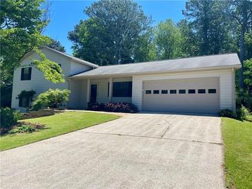Charming home featuring an attached garage, a well-manicured lawn, and a classic driveway at 1028 Gate Post Ln, Lawrenceville, GA 30044