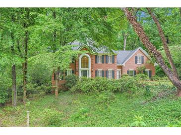 Charming two-story brick home with lush landscaping and mature trees offering privacy at 8470 Valemont Dr, Atlanta, GA 30350