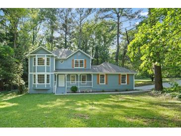 Charming two-story home with a well-manicured lawn, lovely front porch, and beautiful mature trees at 800 Post Road Cir, Stone Mountain, GA 30088