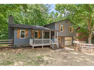 Charming two-story home with a cozy front porch, wooden shutters, and attached garage at 2642 Bridgehampton Sw Rd, Marietta, GA 30064