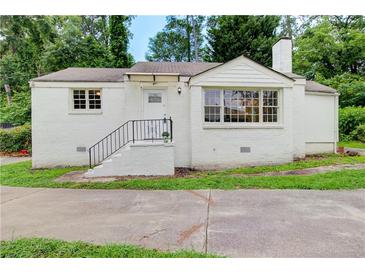 Charming white brick home featuring a well-manicured lawn and updated landscaping at 2742 Alpine Rd, Atlanta, GA 30305