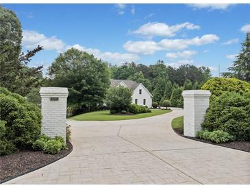 Long driveway leading to a beautiful home with manicured landscaping and a classic white exterior at 590 Arthur Rd, Canton, GA 30115