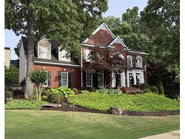 Charming two-story brick home featuring lush landscaping, a manicured lawn, and traditional architectural details at 750 Highview Ct, Woodstock, GA 30189