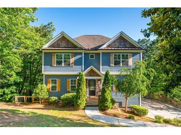 Charming two-story home featuring a blue exterior, shingled accents, lush landscaping, and a curved driveway at 1496 Shadowrock Dr, Marietta, GA 30062