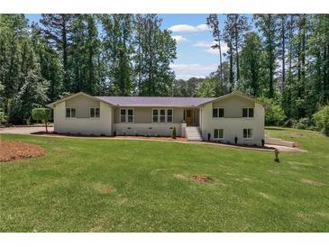 Charming ranch home featuring a lush lawn and mature trees, creating a serene and inviting atmosphere at 145 Devilla Trce, Fayetteville, GA 30214