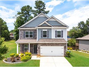 Charming two-story home with stone accents, lush landscaping, and a well-manicured front yard at 3390 Meadow Grass Drive, Dacula, GA 30019