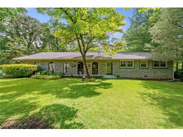 Charming brick home with a well-manicured lawn and mature tree offering plenty of shade at 265 Tamea Trl, Covington, GA 30014