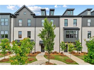 Charming townhome exterior with brick facade, black trim, landscaped yard, and inviting walkways under a partly cloudy sky at 441 Breccia Run, Mcdonough, GA 30253