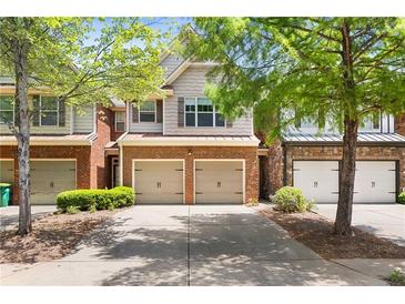 Charming townhome featuring brick accents, a two-car garage, and mature landscaping at 2957 Smith Ridge Trce, Peachtree Corners, GA 30071