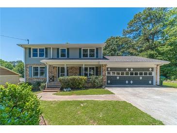 Charming two-story home with brick facade, shutters, landscaped front yard, and a spacious two-car garage at 5166 Vivid Dr, Stone Mountain, GA 30087