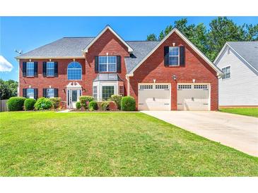 Charming two-story red brick home with a well-manicured lawn and attached two-car garage at 5125 Winding Glen Dr, Lithonia, GA 30038