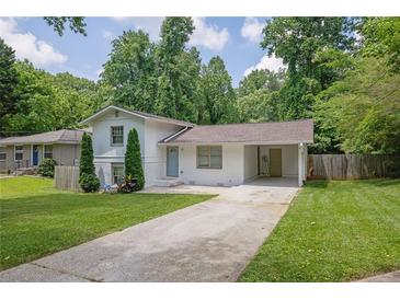 Charming home with a long driveway and a carport, surrounded by lush greenery and a well-manicured lawn at 1585 Melanie Ct, Decatur, GA 30032