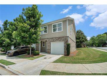 Charming two-story home featuring brick accents, a one-car garage, manicured lawn, and lush green trees at 2039 Wildflower Nw Way, Conyers, GA 30012