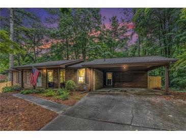 Charming brick home featuring a covered carport, manicured lawn, and patriotic American flag display at 3431 Alcan Way, Tucker, GA 30084